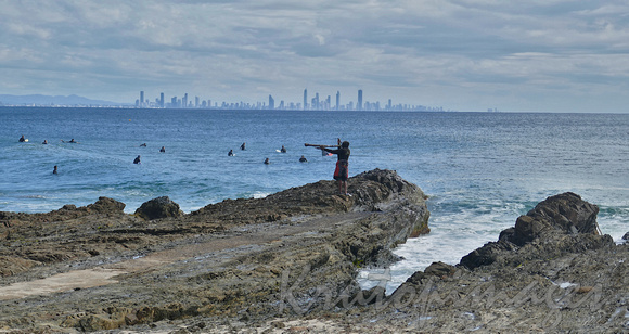 Aboriginal man with didgeridoo stands on Snappers Rocks and repeats  ritual local Gold Coast residents witness daily