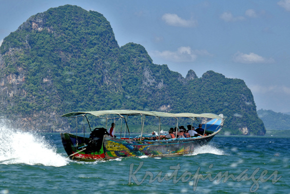 A boat carrying tourists moves at speed between the incredible limestone terrain of Thailand near James Bond Island