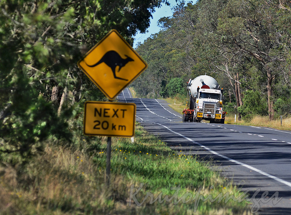 Oversize steel tank load transported on a Victorian country road with warning of kangaroos next 20km