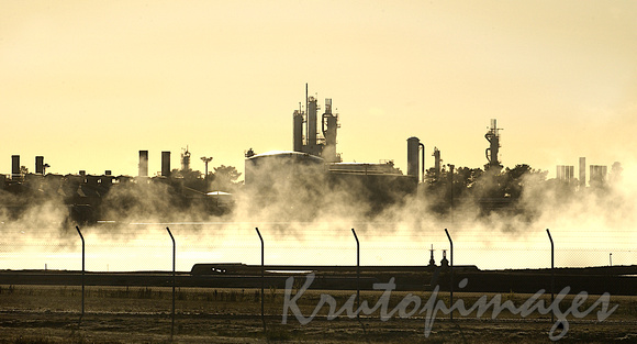 sunrise at the Refinery perimeter fence with steam rising from the cooling ponds