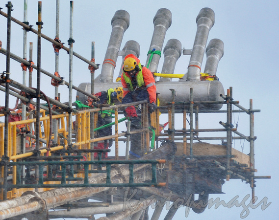 Workers on flare boom offshore installing a new flare tip in inclement weather.