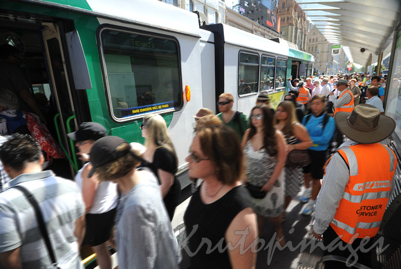 public transport commuters enter thr trams aided by customer service representatives.