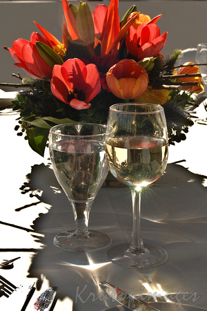 water and wine glass on a dinner table setting with floral arrangement background