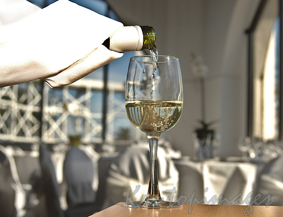 pouring white wine into a glass on a table