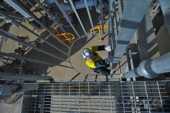 Petrochemicals and plastics Refinery worker from above on steel ladder to another tower level