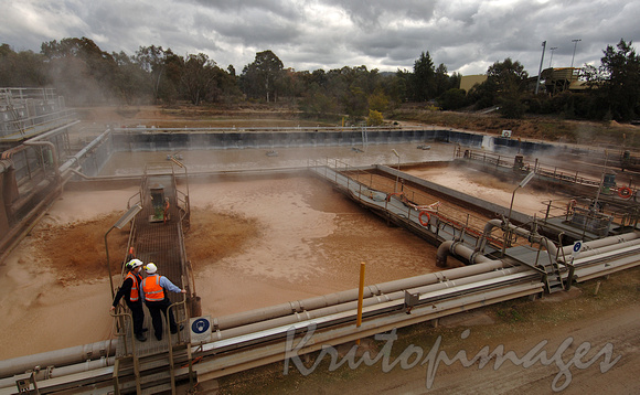 Paper manufacturing- workers stand on the walkway over the mixing-pulp pond as the mixture churns
