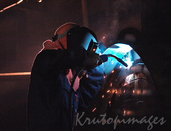 Welder in a confined space works on a dredge bucket
