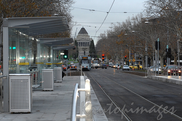 Tram stop on StKilda Road Melbourne with the Shrine in the backdrop at dusk