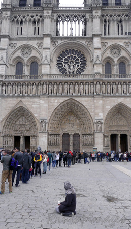 PARIS-France Notre Dame Cathedral crowds & beggar in forecourt.