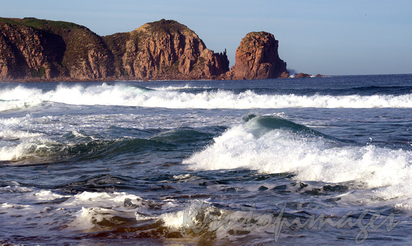 surf and beach showing rocky outcrop on horizon