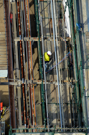 overhead view of a construction worker amongst pipes and scaffolding