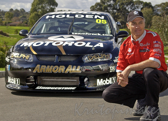 peter Brock crouching in front of his Mobil1 Holden