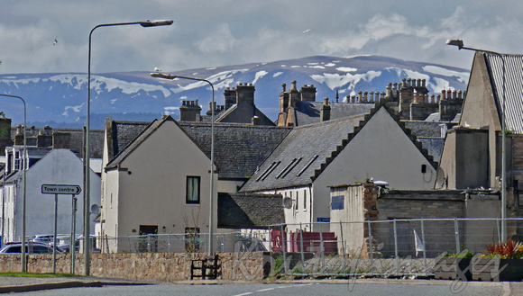 Invergordon Scotland -typical homes and signage with a snow capped backdrop in the highlands