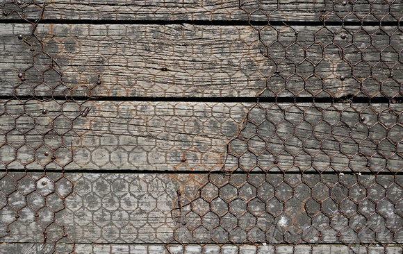 Chicken wire on a timber boardwalk sections removed to reveal mesh imprint