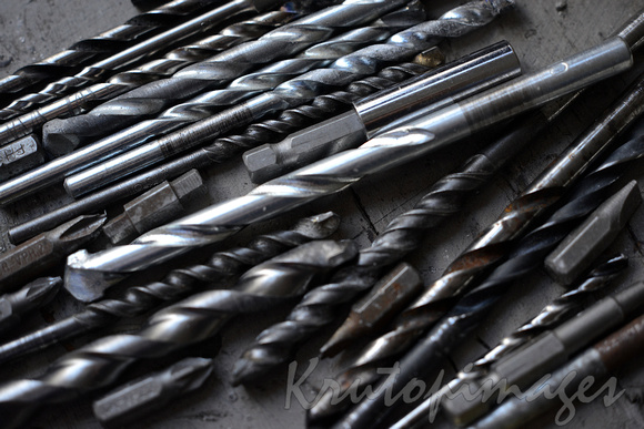 variety of drill bits resting on workshop bench