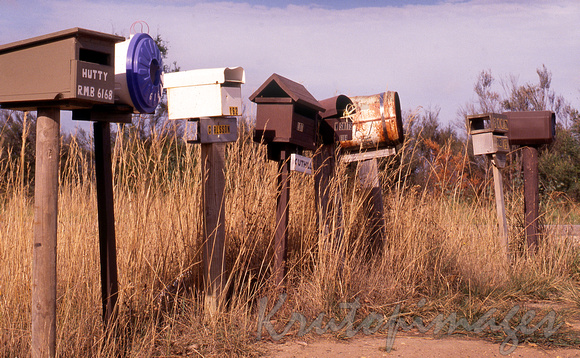 Mailboxes stand as a cluster on the side of a dirt road-Victoria-sc