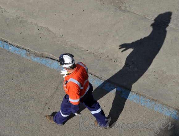 overhead view of a worker on site in ppe casting a long shadow