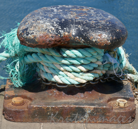 Mooring ropes with entangled face mask on a steel bollard on the pier