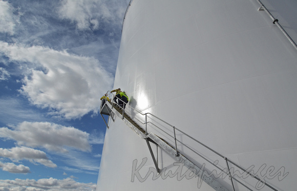 workers climb steps of a fuel storage tank