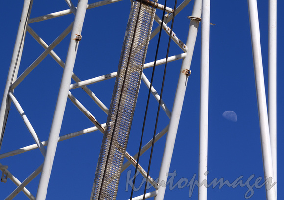 crane booms and early moon at refinery