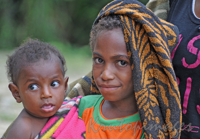 Older daughter cares for little brother in village in apua New guinea Highlands