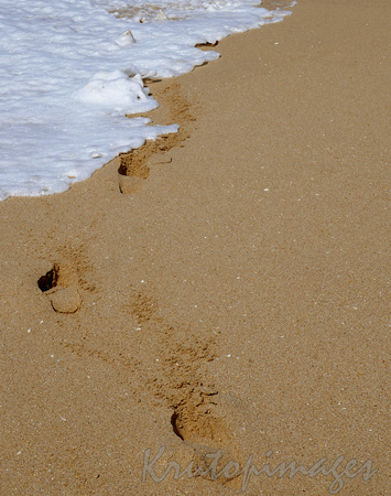 fotprints in the sand to foamy sea