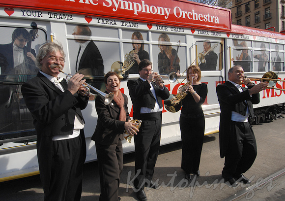 Melbourne Symphony Orchestra members and minister Lynne Kosky laughing performance at tram stop