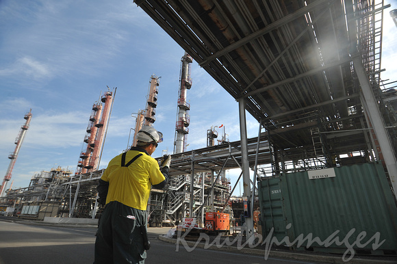 Petrochemicals and plastics REfinery worker communicates with co-worker on a tower