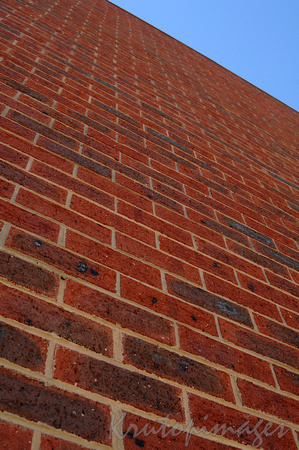 detail of a high red brick wall vertical view with blue sky