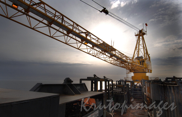 crane operating on platform offshore late in the day.
