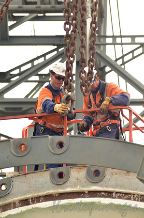 workers in scissor lift and harnesses check load during heavy lift