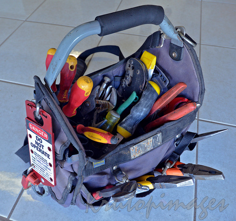 Electricians work bag full of tools sits on a tiled floor g