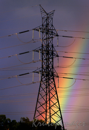 environment- a rainbow late on a stormy day behind a transmission tower